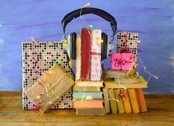 Audio books as birthday present, gift,listening,podcast,literature,education concept with heaps of gift wrapped books,vintage headphone and chain of lights.