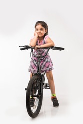 Cute little Indian/asian girl riding on bicycle, isolated over white background 