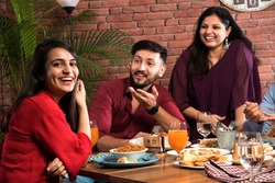 Indian friends eating or dining in restaurant. Asian people in face for get-together, reunion or celebrating party. Coffee Shop Celebration Friendship Togetherness concept