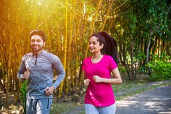 Indian asian young Couple jogging, running, exercising or stretching outdoors in park or nature