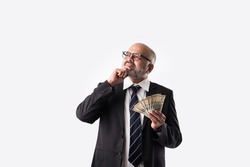 Portrait of happy Indian asian senior businessman holding indian currency notes of five hundred denominations