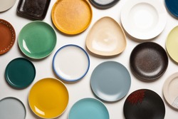 Empty colourful ceramic plates in group over white background, top view