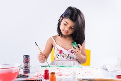 Cute little Indian/Asian Girl enjoying Painting at home with paper, water colour and art brush. Selective focus