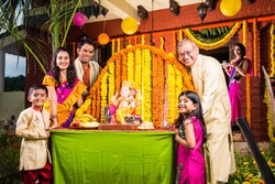 cheerful indian  family welcoming lord Ganesha idol on ganesh festival or ganesh chaturthi on palkhi decorated with garland flowers