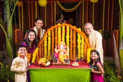 cheerful indian  family welcoming lord Ganesha idol on ganesh festival or ganesh chaturthi on palkhi decorated with garland flowers