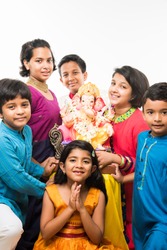 Group of Indian Kids holding Ganpati Idol on Ganesh festival or Chaturthi, welcoming god. Standing isolated over white background