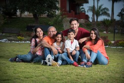 Portrait of Happy Indian/Asian Family while sitting on Lawn, outdoor
