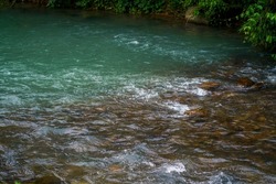 River stream blue color water flowing on stones. nature background.