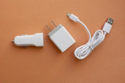 top view white color telephone chargers,usb car charge,home and cable on orange background