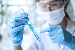 Scientist or medical in lab coat holding test tube with reagent, Laboratory glassware containing chemical liquid, Microscope, Biochemistry laboratory research.