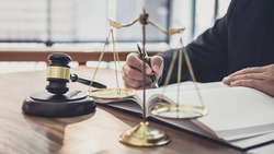 Male lawyer or judge working with contract papers, Law books and wooden gavel on table in courtroom, Justice lawyers at law firm, Law and Legal services concept.
