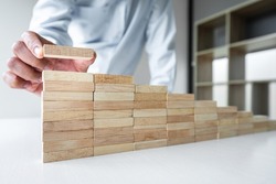 Risk To Make Business Growth Concept With Wooden Blocks, hand of businessman has piling up and stacking a wooden block, Alternative risk concept, plan and strategy in business.