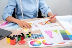 Professional women fashion designer stylist working and thinking decide making new clothes collection material product and choosing a color swatch.
