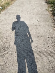 Shadow of a grown man on a cement road
