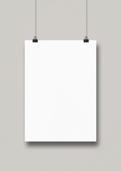 White poster hanging on a clean wall with clips. Blank mockup template
