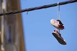 Old sneakers hanging from a cable.