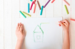 A child draws a house with crayons. House. Multicolored crayons, pastel.
