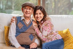 Portrait of beautiful Latin woman hugging her older father smiling and looking at camera.