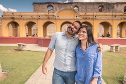 Young tourists are enjoying their vacations in the colonial city on a sunny day - Hispanic couples in love walk through the park of a city.
