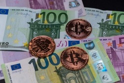 Golden Bitcoin coins lied on top of 100 Euros and 500 Euros bank notes. Gold bitcoin on one hundred and five hundred euros banknotes. Cryptocurrency concept, bitcoin and Euro banknotes.