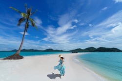 A young asian woman wears a dress and dancing on the beach in the summer alone on her vacation. Travels to andaman sea Laem Had Beach, Koh Yao Yai, Phatthalung, Thailand.