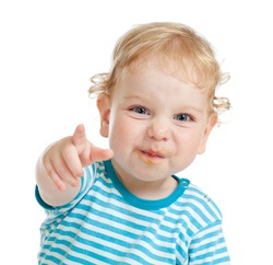 funny curly child with dirty lips pointing by finger directly to camera
