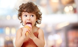 Kid eating ice cream in cafe. Funy curly child with icecream outdoor.