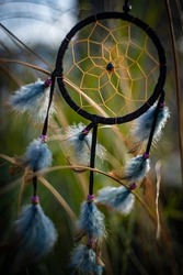 Dream catcher with feathers threads and beads rope hanging and nice bokeh background - art picture with depht of focus