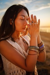 Bohemian chic gypsy happy free asian woman with manicure wearing hands jewelry accessories and white dress. Boho detail close up at sunset.