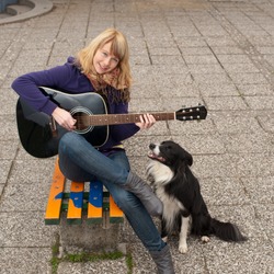 Young female guitar performer posing with her instrument and her dog