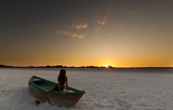 Girl with her back raised in a boat at sunset. Take horizontan with space for advertising text.