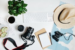 Beautiful hipster flatlay with hat, dslr camera, lens, coffee, map, flower, notebook and binocular. Working space surface top view. Creative work table for photographer, traveller, blogger 