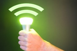 Hand holds a Lifi symbol with glowing bulb combined with wifi symbol