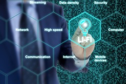 IT expert in a blue suit touches a Lifi symbol in a hexagon grid surrounded by topic related words like high speed or communication