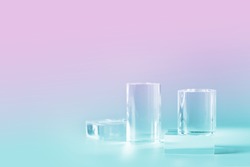 Acrylic empty podium for product presentation on nein pink and blue colored background, transparent geometric pedestals