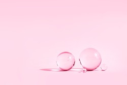 Abstract backdrop with glass spheres on pink pastel color background with sun reflections, monochrome 