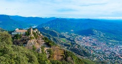 a panoramic view of the Serra de Queralt moutain, in Berga, Catalonia, Spain, highlighting the Mare de Deu de Queralt Shrine on the left and the town of Berga in the valley, on the right