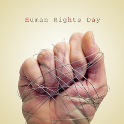 a man hand tied with wire and the text human rights day on a beige background