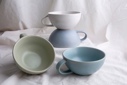 Image of Pottery, light Pastel ceramic cups on the white cloth or vintage white look fabric background