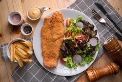 American Deep fried Pangasius dory fish fillet steak, chips and vegetables in the studio lighting