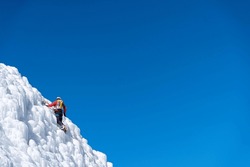 A climber in a red suit climbs an icy white mountain