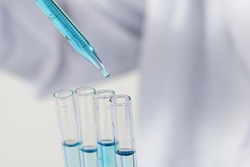 Biochemistry laboratory research, Scientist or medical in lab coat holding test tube with using reagent with drop of color liquid over glass equipment working at the laboratory.