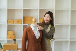 Side view of pensive woman seamstress with measuring tape standing near mannequin taking measurements while sewing new fashion dress in modern atelier