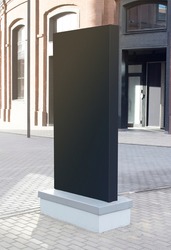 Blank black vertical pylon stand mockup brick building, side view. Empty light box or commercial tower for city information mock up. Clear media or promotion frame signage mokcup template.