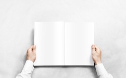 Hand opening white journal with blank pages mockup. Arm in shirt holding clear magazine template mock up. Man reading double-pages book first person view. Mag layout spread.
