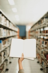 Opening book in the middle of blurry image of library aisle