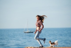leisure recreation pursuit of active sport woman and little chihuahua dog pet running along sea coast with boat
