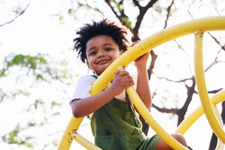 Cute African American little kid boy having fun while playing on the playground in the daytime in summer. Outdoor activity. Playing make believe concept. Outside education