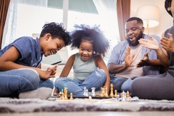 Cute African American children playing chess at home