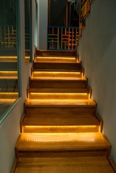 Illuminated staircase with wooden steps and illuminated at night in the interior of a large house.